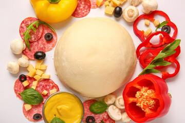 Raw dough and ingredients for preparing pizza on white background