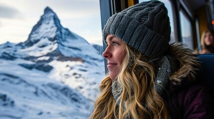 Fototapeta na wymiar Happy female traveler looking out the window traveling by train in beautiful winter mountains, travel concept