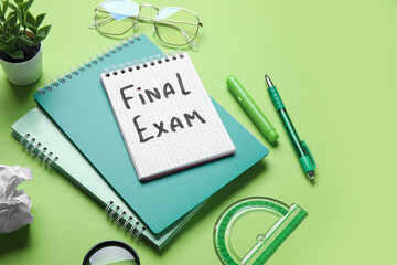 Notebooks with text FINAL EXAM, different stationery and eyeglasses on green background