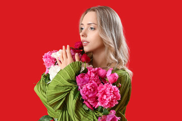 Young woman with beautiful peony flowers on red background