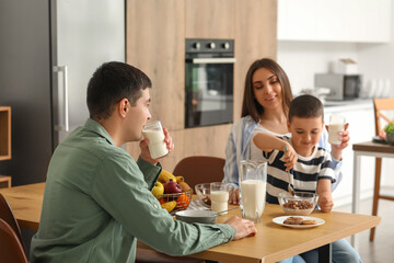 Little boy with his parents having breakfast in kitchen