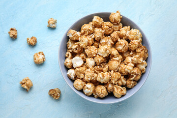 Bowl with tasty popcorn on blue background