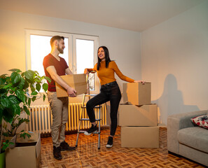 Couple just moved in into the apartment, talking and holding boxes in arms 