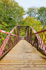 Fototapeta na wymiar Rustic Red Pedestrian Bridge in Autumn Park - Eye-Level View
