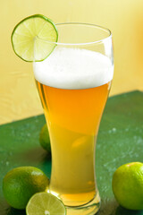 Glass of cold beer with lime on table