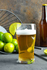 Glass of cold beer with lime on table