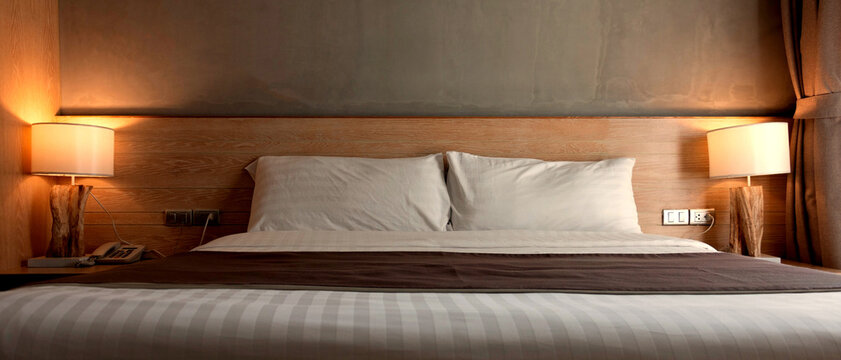 two white pillows on bed with lamp light at night in bedroom
