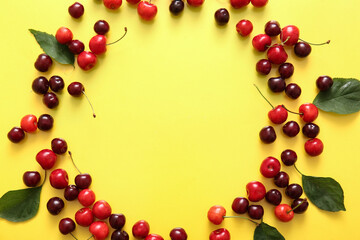 Frame made of sweet cherries and leaves on yellow background