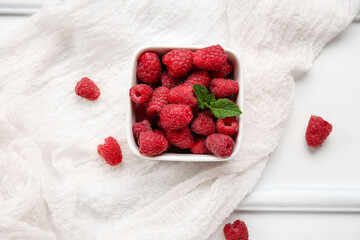 Bowl with fresh raspberry and mint on light wooden background, closeup