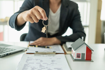 A real estate salesperson holds a small house model to introduce customers. Model house project and...