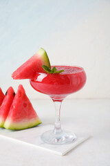 Board with glass of tasty watermelon juice and mint on white table