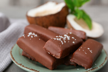 Plate with tasty chocolate covered coconut candies on grey background