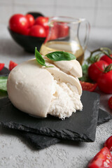 Tasty Burrata cheese with basil and tomatoes on grey table