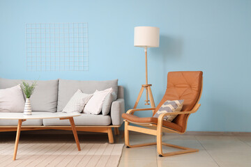 Comfortable armchair, sofa and table near blue wall