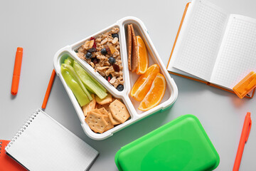 Lunchboxes with delicious food and different stationery on white background
