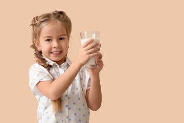 Cute little girl with glass of tasty milk on beige background