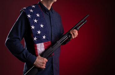 Armed citizen holding a shotgun with an American flag over his shoulder