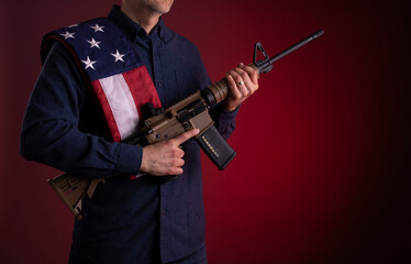 Armed citizen holding an AR rifle with an American flag over his shoulder