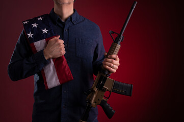 Armed citizen holding an AR rifle with an American flag over his shoulder