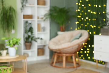Blurred view of living room with green plants, armchair and glowing lights