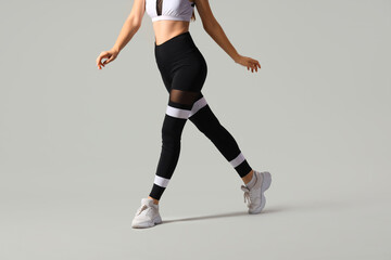 Sporty young woman in leggings on light background