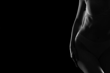 Silhouette of young woman in underwear on dark background, closeup