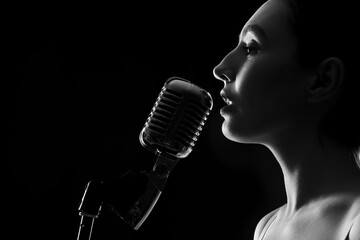 Silhouette of female singer with microphone on dark background, closeup