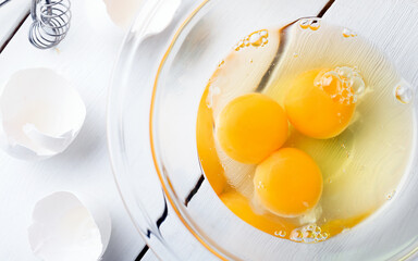 Egg yolks in a glass bowl on white wooden background
