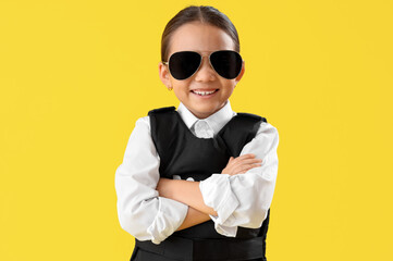 Cute little police officer in sunglasses on yellow background. Opposite Day celebration