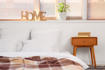 Big bed and table with books in light bedroom