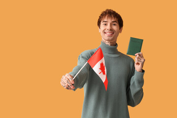 Handsome young man with flag of Canada and passport on yellow background. Immigration concept