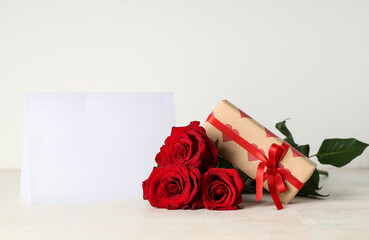 Beautiful roses, gift box and blank greeting card on grey background. Valentine's Day celebration