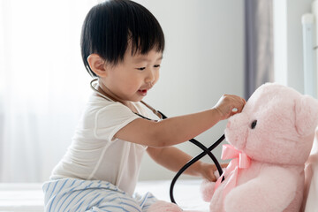 Young cute Asian girl Playing doctor with favorite toys. Sitting on the bed. little girl having...