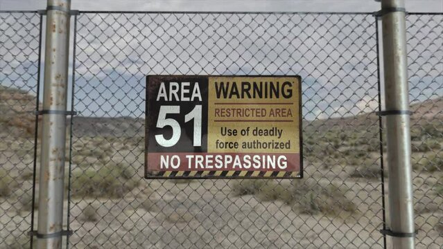 High quality 3D CGI render with a smooth dollying-in shot of a chainlink fence at a secret military installation in a desert scene, with an Area 51 Warning Restricted Area sign,