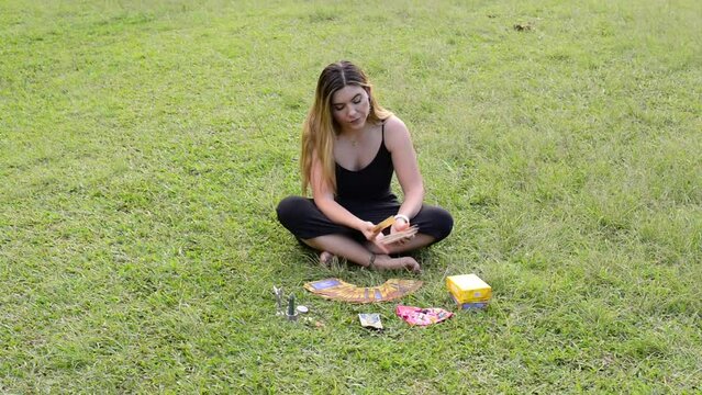 Girl shuffles angelic oracle tarot cards on green grass. Angeology and spirituality