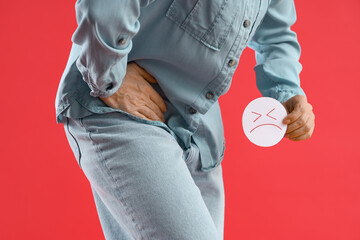 Mature woman with sad smile on red background, closeup. Hemorrhoids concept
