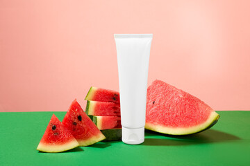 An unlabeled cosmetic bottle container for cream of facial cleanser decorated with fresh watermelon slices on pink background. Mockup for natural cosmetics advertising. Health and beauty theme