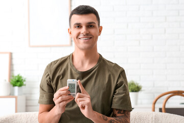 Diabetic young man with glucometer at home