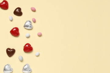 Tasty heart-shaped chocolate candies with dragee on yellow background. Valentine's Day celebration