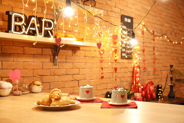 Obraz na płótnie Canvas Bar counter with cups of hot chocolate, hearts and glowing lights, closeup. Valentine's Day celebration