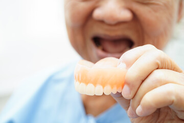 Asian senior woman patient wearing teeth denture into her mouth for chew food.