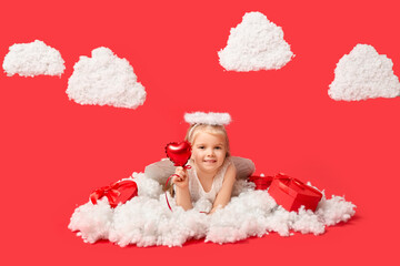 Cute little girl dressed as cupid with gift boxes, heart-shaped balloon and clouds lying on red background. Valentine's Day celebration