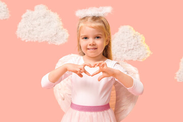 Cute little girl dressed as cupid showing heart gesture on pink background. Valentine's Day celebration