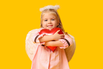 Cute little girl dressed as cupid with heart-shaped balloon on yellow background. Valentine's Day...