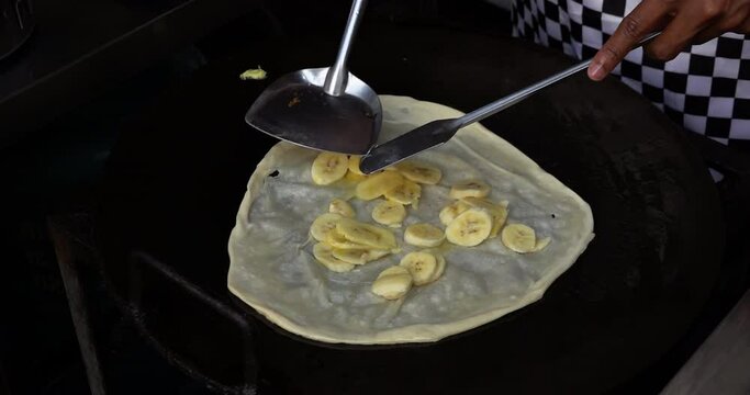 Slow Motion Wrapping the roti stuffed with sliced bananas frying in pan