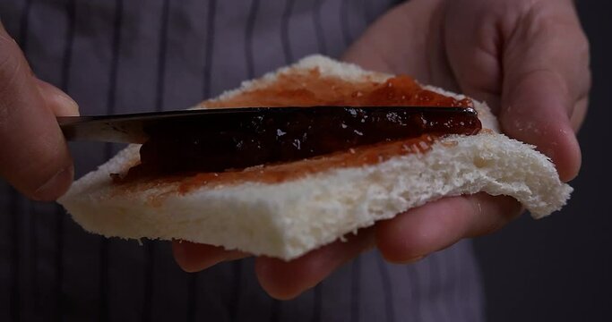 Slow Motion Close-up View of a sandwich bread spreading with strawberry jam