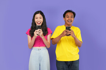 Young amazed couple Asian man and a woman holding  their phone .isolated on a plain purple color background