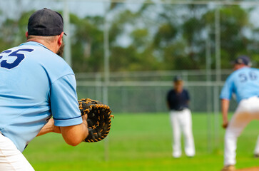 Baseball game, first baseman is getting ready to catch a ball from a pitcher, base coach in the...
