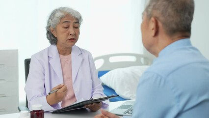 An elderly Asian male patient answers questions from an elderly female doctor. health advice and discuss comprehensive health care in a healthcare environment. Health insurance concept.