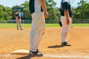 Baseball game, runner on the third base is watching the pitcher and getting ready to run to home...